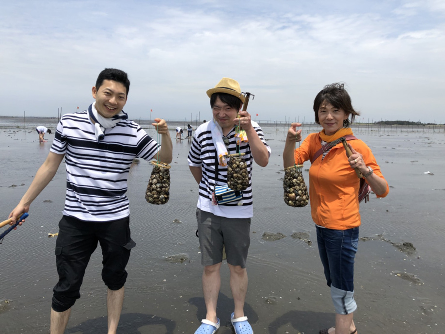 潮干狩りで収穫したあさりをもつ恩田商店の面々