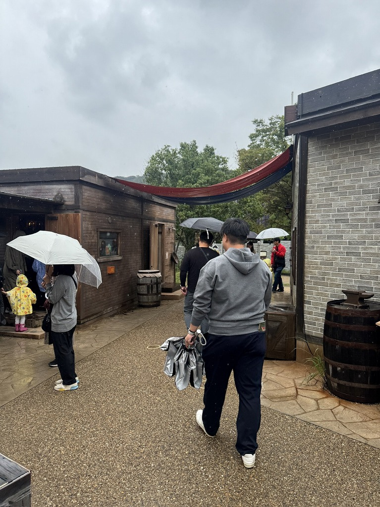 画像4:雨の中、傘をさして『ドラゴンクエスト アイランド』の街並みを歩く来場者たち。