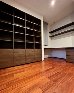 【洋室】 | 越谷大成町 /積水ハウス高級邸宅「IS ROYÉ」/5LDK+2WIC | 書斎からビルトインガレージへ直接出入り可能。室内から愛車を眺められる特別な空間です。濃色木目のデスクと壁面収納が映える、重厚で静穏なプライベートルーム。