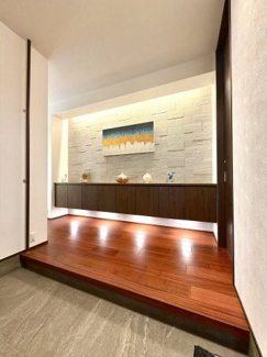 【玄関】 | 越谷大成町 /積水ハウス高級邸宅「IS ROYÉ」/5LDK+2WIC | 邸宅の顔にふさわしい、洗練された玄関ホール。間接照明に照らされた天然木のフロアと飾り棚が、ゲストを上品にお迎えします。毎日の出入りが豊かになる空間です。