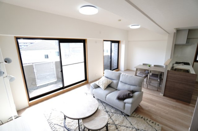 【居間・リビング】 | 【リノベ済】クレイドル西原駅東 | 【約16.9帖LDK】
大きな開口部からやわらかな光が差し込み、
ダイニングとリビングがゆるやかにつながる心地よい空間。
キッチンとも視線が通り、日常の動きが自然に整う、
明るく開放感のある住まいです