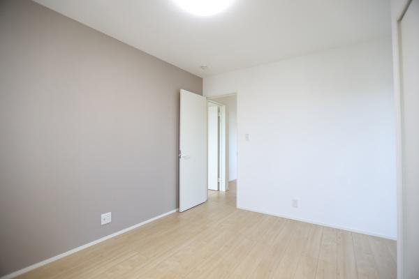 AG-HOUSE 萩原A棟の洋室|落ち着いた色合いの壁がアクセントになっています。広々とした空間でゆとりがあります。ドアや床のデザインもシンプルで現代的です。照明がしっかりと部屋全体を明るく照らします。清潔感のある洋室です。