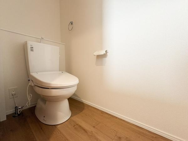 大字鴛野1期1号棟のトイレ|明るく清潔感のあるトイレです。シンプルなデザインで圧迫感の少ない広がりを感じる空間になっています。床材には木目調が採用され温かみがあります。