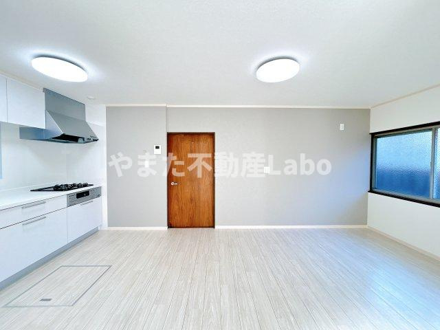 倉吉市大正町2丁目中古戸建の居間・リビング|キッチン別アングルです。白を基調としたキッチンにグレーのアクセントクロス、ブラウンの建具が差し色となっておしゃれな仕上がりです。