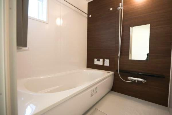 タマタウン青葉台　2号地の浴室|木目調のアクセントパネルがおしゃれなバスルームです。浴槽はゆったりとしたサイズ感で快適です。壁付けの鏡やカウンターがすっきりとした印象を与えます。小窓からの換気も便利です。