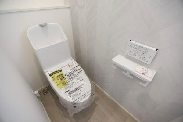 タマタウン青葉台　2号地のトイレ|シンプルなデザインのトイレで清潔感があります。壁の色合いが落ち着いた印象を与えます。ペーパーホルダーや操作パネルも使いやすい配置です。