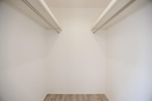 タマタウン青葉台　2号地の収納|シンプルなデザインの収納スペースです。壁面にハンガーパイプが設置されています。床は落ち着いた色合いのフローリングです。無駄のない空間が特徴です。