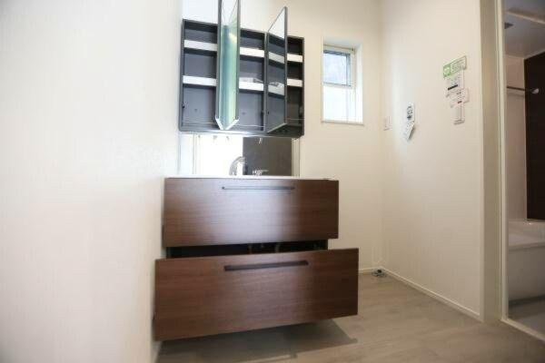 タマタウン青葉台　2号地の独立洗面台|木目調の洗面台が空間に落ち着きを感じさせます。大きな引き出しが二つあり収納スペースもしっかり確保されています。ミラーキャビネットも広々としており日用品の整理整頓に便利です。