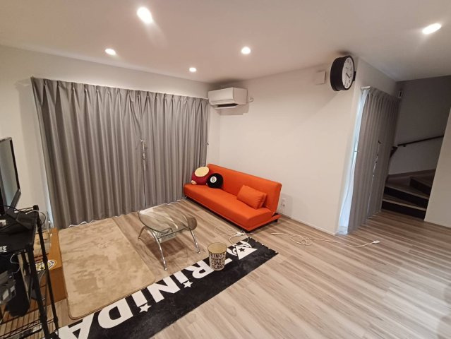 西条市小松町新屋敷甲　中古戸建の居間・リビング|南向きの窓から暖かな光が差し込むリビング。中2階を感じさせるリビング階段が、家族の気配を常に感じさせてくれる。ウッドデッキへと繋がる開放感あふれる空間で、家族が自然と集まる温かい時間を育めます