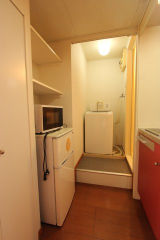 プチ・フルールの設備|キッチン向かいに冷蔵庫・電子レンジ　奥に洗濯機 浴室があります。