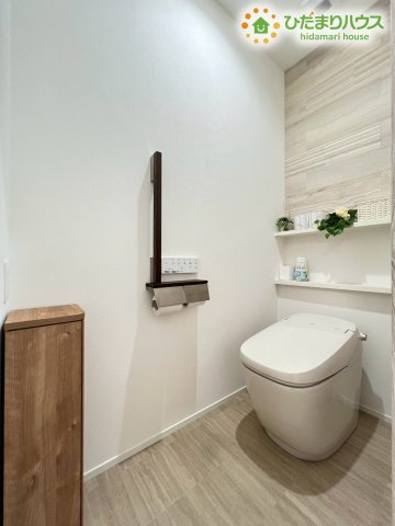 熊谷市原島　中古一戸建てのトイレ|木目調のアクセントウォールがおしゃれなトイレ空間！タンクレストイレは見た目がスッキリしているだけでなくお掃除がしやすいのも嬉しいポイント♪予備のペーパーを置ける棚や手すりも付いていて利便性もバッチリ！