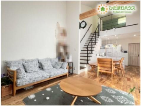 熊谷市原島　中古一戸建ての居間・リビング|吹抜の大きな梁が開放感を演出するリビングは、無垢材の床が心地よく、裸足で歩きたくなる空間です！階段下のデッドスペースを活用した収納など、機能的な工夫が満載で、家族が自然と集まりたくなる温かさがあります