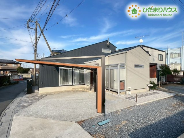 熊谷市原島　中古一戸建ての外観|青空に映えるネイビーのガルバリウム調の外壁と木目調のアクセントが目を引くおしゃれな外観です！大型のカーポートが設置されているので雨の日でも濡れずに車へ乗り降りがスムーズにできて日々のお買い物も楽々♪
