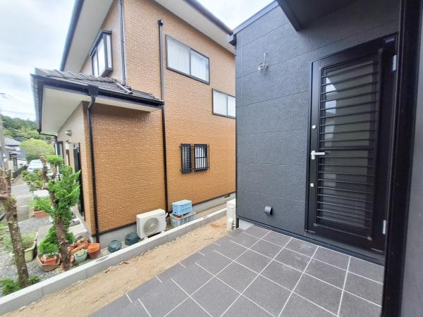 AG-HOUSE　梅が丘　A棟の玄関|タイル張りの玄関アプローチが印象的です。シンプルなデザインが建物と調和しています。玄関扉はスタイリッシュなブラック仕様です。隣家との距離もしっかり確保されています。整理された外観が好印象です。