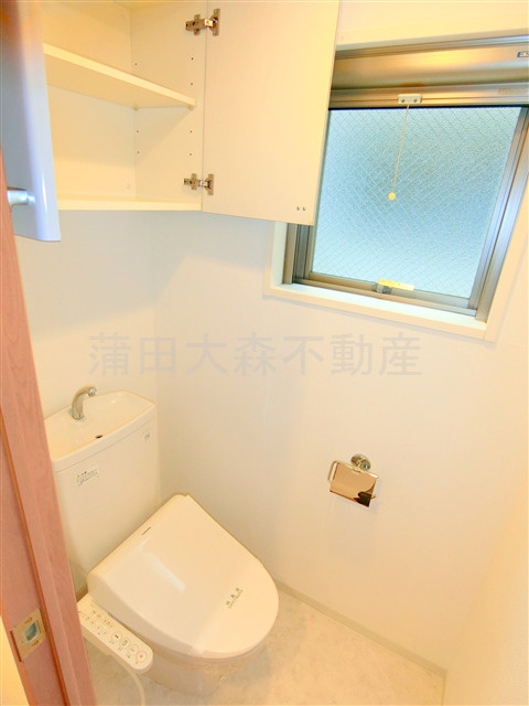 プロスペクト大森海岸のトイレ|窓と吊戸棚収納、温水洗浄便座付きのトイレ
