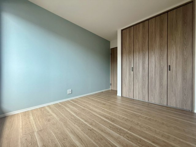 高知市一宮徳谷 新築建売の洋室|大容量クローゼットを備えた使いやすい洋室。木目の床とブルーの壁が調和した、落ち着きのある空間です。