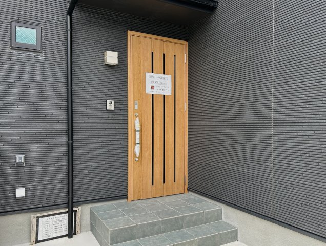 高知市潮新町　新築一戸建ての玄関|ダークトーンの外壁に木目ドアがアクセント☆