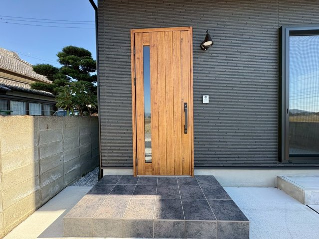 南国市田村乙 中古一戸建の玄関|木目調の玄関ドアが映えるスタイリッシュな外観。重厚感と温かみを両立したデザインです。