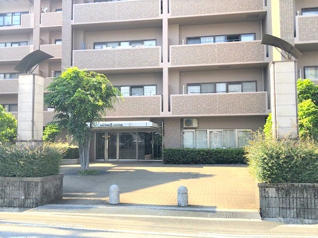 アルファステイツ旭駅前の外観|エントランス入口付近。緑の植栽が映えるタイル張りの外観です。