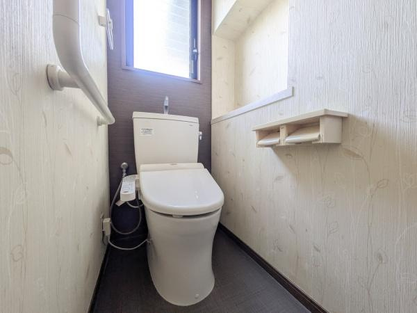 梅が丘2丁目　戸建てのトイレ|窓付きで明るい空間が広がるトイレです。手すりが設置されており移動のサポートが充実しています。使い勝手の良いペーパーホルダーも備わっています。清潔感あふれる内装が印象的です。