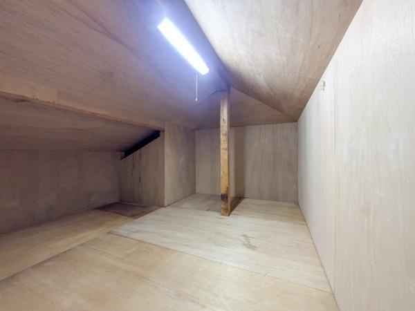 梅が丘2丁目　戸建ての収納|天井裏スペースを有効活用した収納です。十分な広さがありさまざまな物を整理しやすい空間になっています。照明もしっかり設置されており明るさを確保しています。木目調の内装で落ち着いた雰囲気が広がります。