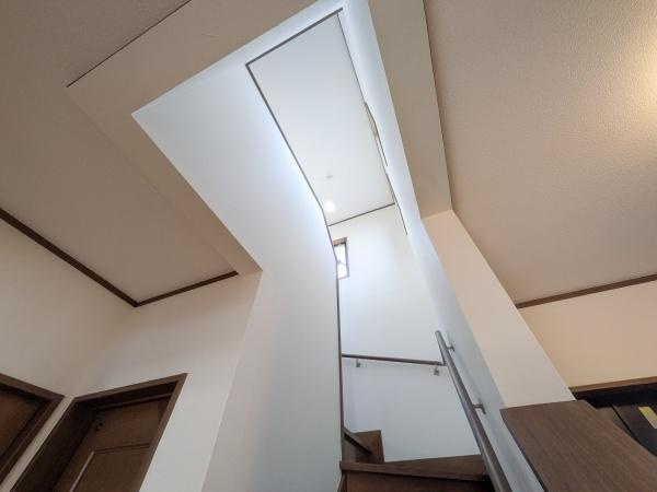 梅が丘2丁目　戸建ての内装|吹き抜けがあることで空間が開放的に感じられます。階段周りは明るく落ち着いた雰囲気が広がっています。シンプルなデザインが室内をすっきりと見せています。手すりや壁のアクセントも印象的です。