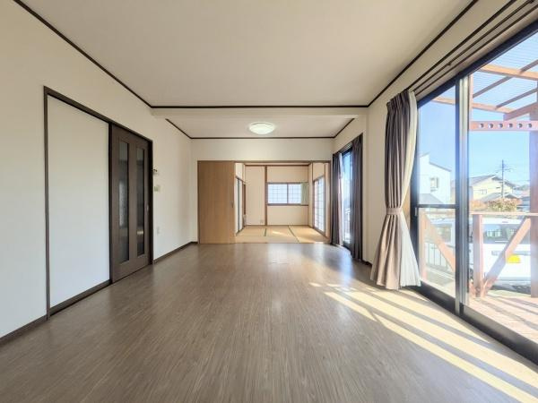 梅が丘2丁目　戸建ての居間・リビング|大きな窓から自然光が差し込み開放感あふれるリビングです。隣接する和室との一体感が魅力です。フローリングが清潔感を演出しています。カーテン付きで日差しの調整もしやすい空間です。