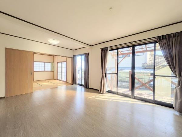 梅が丘2丁目　戸建ての居間・リビング|明るい光が差し込むリビングは開放的な空間が広がっています。大きな窓からは外の景色を楽しめ通風も良好です。隣接する和室はスライドドアで仕切れるため使い勝手も柔軟です。