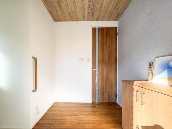 角子原　戸建ての玄関|木目調の天井と床が落ち着いた雰囲気を演出しています。壁際の手すりが設置されており安心感があります。玄関収納も備え付けられており片付けがしやすい空間です。