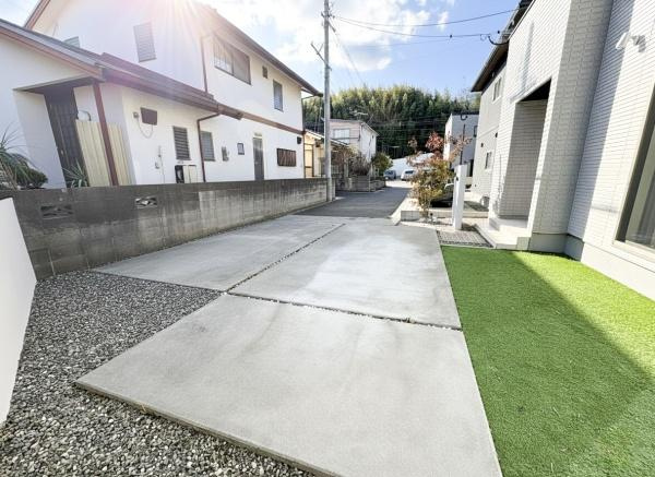 角子原　戸建ての駐車場|広々とした駐車スペースが特徴です。アプローチもゆとりがあり車の出し入れがしやすい設計です。敷地内には人工芝や砂利も整備されており手入れのしやすさも魅力です。住宅前面の開放感がポイントです。