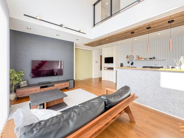 角子原　戸建ての居間・リビング|明るいリビングは吹き抜け天井と大きな窓から光が差し込み開放感があります。ナチュラルな木目フローリングが温かな雰囲気を演出しています。