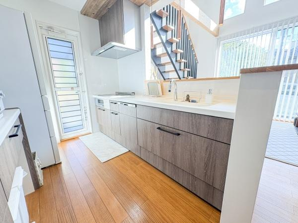 角子原　戸建てのキッチン|明るい日差しが差し込むキッチンです。広々とした作業スペースが特徴的です。ナチュラルな木目調のデザインが印象的です。水回りも使いやすそうな配置です。階段下の開放感も魅力です。