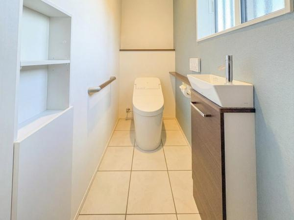 角子原　戸建ての独立洗面台|明るく清潔感のある洗面台・洗面所です。壁付きの手すりや収納棚があり使いやすさも考慮されています。洗面スペースはコンパクトで動線もスムーズです。木目調のキャビネットが温かみをプラスしています。