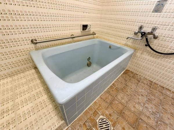 緑が丘4丁目中古の浴室|浴室にはシンプルなデザインの浴槽が設置されています。手すりが備え付けられているため使いやすさにも配慮されています。壁や床のタイルがレトロな雰囲気を演出しています。