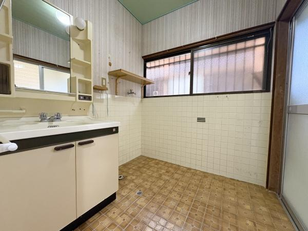緑が丘4丁目中古の独立洗面台|広々とした洗面所で収納スペースもしっかり確保されています。大きな窓から採光があり明るさを感じられます。棚も設置されており使い勝手の良い設計です。清潔感のある壁面と床材が印象的です。
