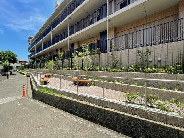 アンビシャスガーデン鶴瀬 の外観|マンションの裏側の通路にはコモンガーデンがあり、ベンチも設置しております。