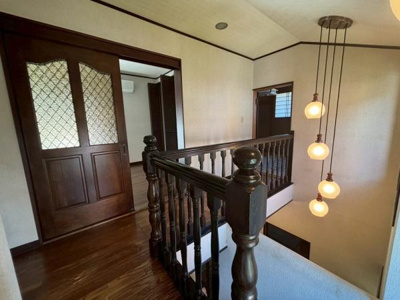 【その他】 | ●草加市氷川町・戸建● | 落ち着いた雰囲気の漂う廊下が印象的です。木の温もりを感じる手すりがアクセントになっています。照明のデザインが空間を引き立てています。仕切りのあるドアでプライベート感も演出されています。