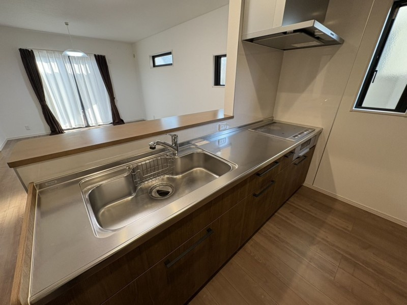 松山市空港通二丁目のキッチン|IHクッキングヒーター採用のシステムキッチンは、油汚れもサッと拭くだけでお手入れ完了。火を使わない安心感もあり、お子様と一緒に今日のご飯を作る時間は、毎日を彩る大切なひとときになりそう。