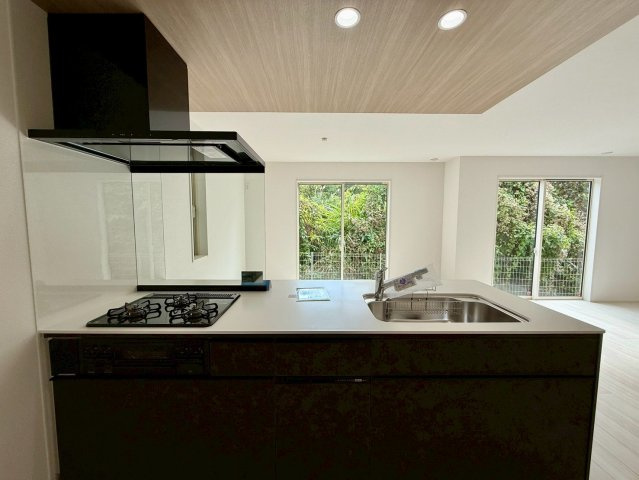 グラファーレ浦添市前田・２号棟のキッチン|レンジフード＆ガスコンロ３口＆調理台＆流し台／キッチンからのリビングの眺め