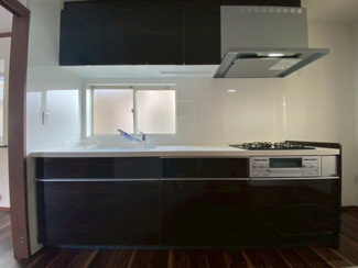 【キッチン】 | かまとり住宅のリフォーム戸建て「リ・スタイル」 | シックな黒のパネルが映える、スタイリッシュなシステムキッチンです 。シンク前には窓があり、明るい光の中で作業ができます 。上下の豊富な収納を備えており、デザイン性と機能性を両立した空間です 。