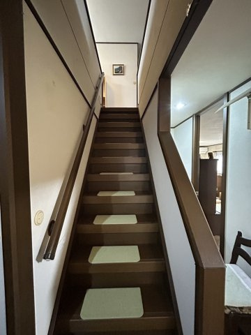 安佐北区亀山南3丁目　土地建物の内装|手すり付きで昇り降りしやすい階段は日常の移動を安心して行える設計です。段板には滑りにくいマットが敷か