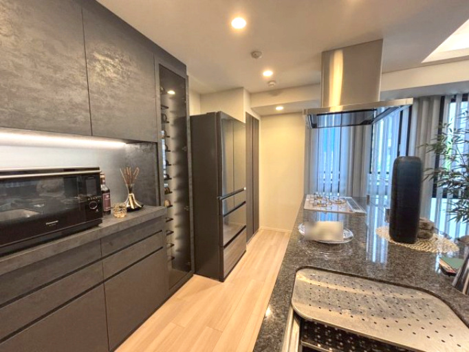 グラン レ・ジェイド白壁 月露ノ邸のキッチン|重厚感ある石目カウンターとダークトーンの面材が調和したキッチン。