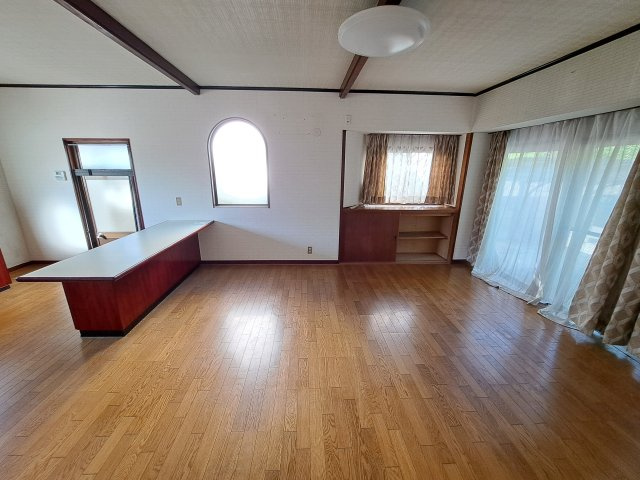 西条市飯岡2480-36　中古戸建の居間・リビング|西向きの大きな窓からたっぷりと陽光が降り注ぐ、家族の集いの場。広い敷地を活かした庭との繋がりを感じられ、開放感あふれる暮らしが叶う。ソファを置いてゆったりと寛げる、家の中心となる暖かなリビング。