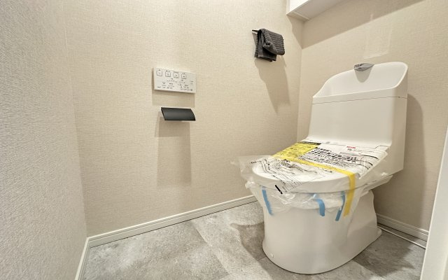 鴨居第一ハイツイーストヒルのトイレ|温水洗浄便座のトイレ設備です♪トイレ上部にはあると便利な吊戸棚やタオル掛けを設置♪