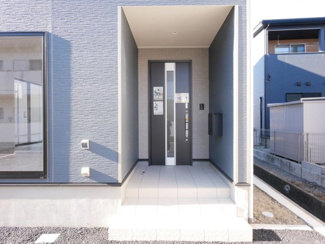 【玄関】 | 甲斐市西八幡 オール電化新築戸建 全2棟 1号棟 車並列3台 | 大きな庇付きの玄関