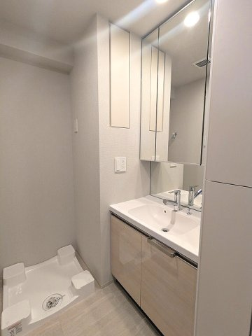 geo ent上野稲荷町の洗面所|トイレと独立した洗面脱衣室に洗濯機置場あります、三面鏡付ハンドシャワー付洗面台、洗濯機置場は排水口のお手入れしやすい様に手前中央に配置し、足高の防水パンです