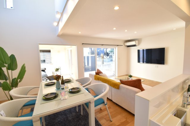 ゼロキューブ　吹き抜けのあるモダン住宅の居間・リビング|白を基調としたLDK+吹き抜けは家族が自然と寛げる場所にピッタリです。リビングと洋室の前には広大なウッドデッキを設置。プライバシーが守られるように配置されているため外からは見えません。