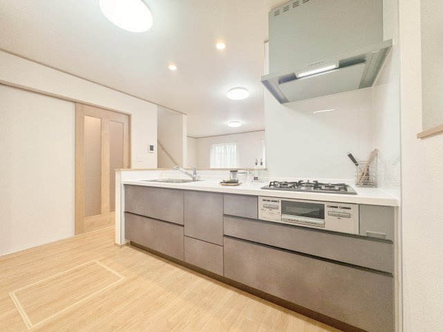 江戸川区東葛西３丁目　新築分譲住宅　全３棟のキッチン|【システムキッチン】豊富な収納はもちろん、大型シンクに３口グリル付きコンロ・浄水器など使いやすさ重視の対面式システムキッチン。ご家族と楽しく会話をしながら料理もできます♪※写真は施工例です