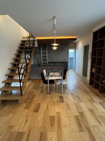 高知市朝倉本町1丁目　建売住宅の居間・リビング|木の温もりと黒のアクセントが調和したナチュラルモダンなLDK。吹き抜け階段が空間に広がりを生み、家族の気配を感じられる心地よいリビングです。