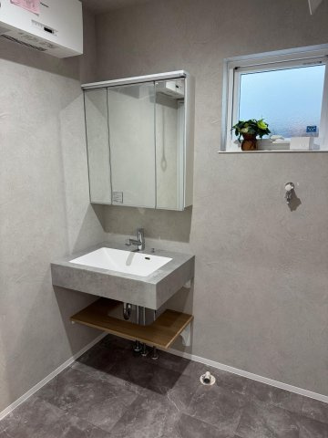 高知市朝倉本町1丁目　建売住宅の独立洗面台|モルタル調の洗面台に木の棚がアクセント。生活感を抑えたデザイン性の高い一角。